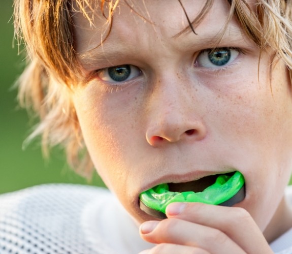 Young boy putting athletic mouthguard into his mouth