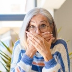 Surprised older woman covering her mouth with her hands