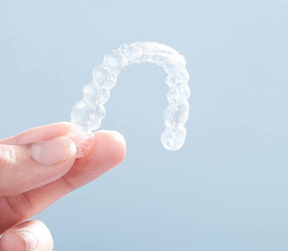 Close up on a person holding an Clear Aligners clear aligner