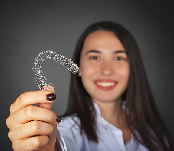 Woman holding up an Clear Aligners tray