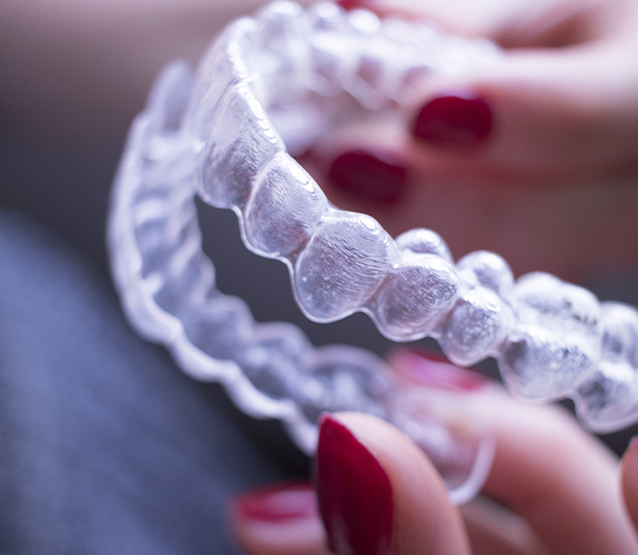 Hand holding an individual Clear Aligners clear braces tray