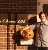 Young Doctor Siewert smiling with a jack o lantern outside of his dental office